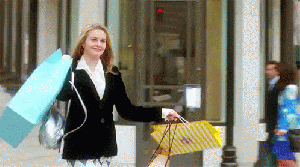 gif-compras Gif da Cher, do filme As Patricinhas de Beverly Hills, fazendo compras. Ela está segurando sacolas nas duas mãos, sorrindo e andando.