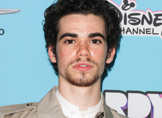 Cameron Boyce posando em carpet; ele está com expressão séria olhando para câmera