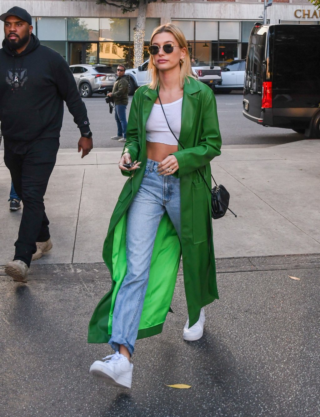 Hailey Bieber de calça jeans, camiseta branca e casaco verde