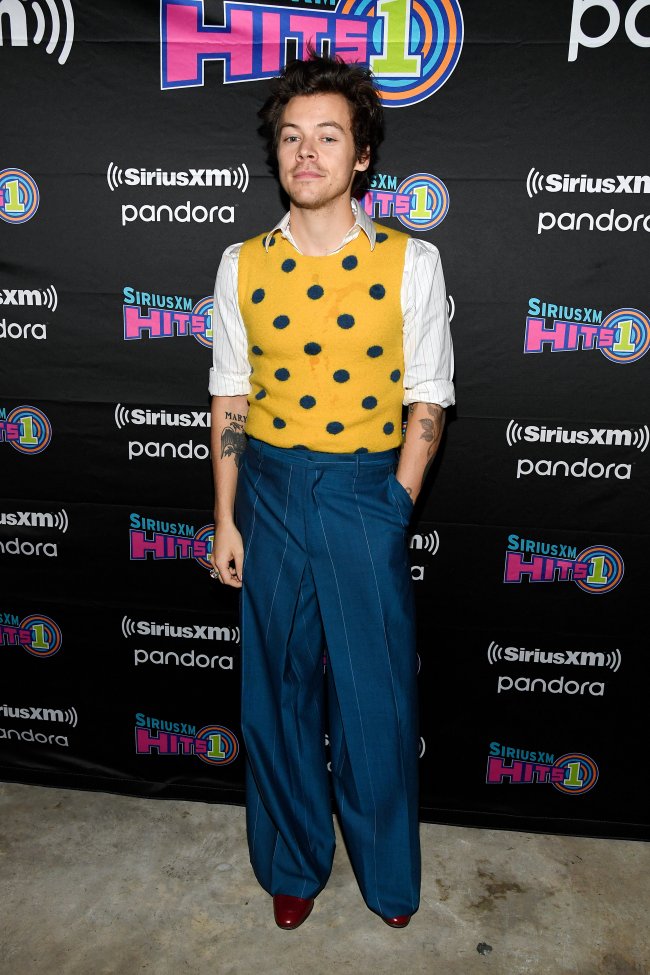 Harry Styles usando colete amarelo de poá por cima de uma camisa branca