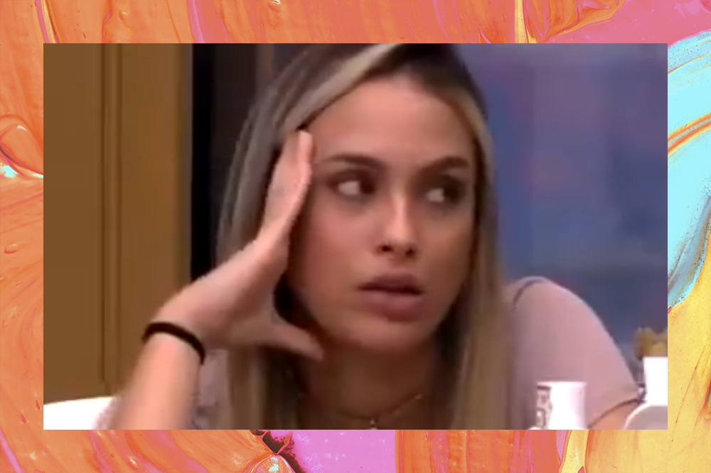 Sarah no BBB21. Com uma mão no rosto, ela olha com olhar desconfiado para alguém