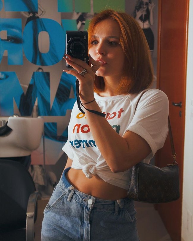 Larissa Manoela com bolsa baguete e câmera fotográfica em mãos Larissa Manoela com bolsa baguete e câmera fotográfica em mãos