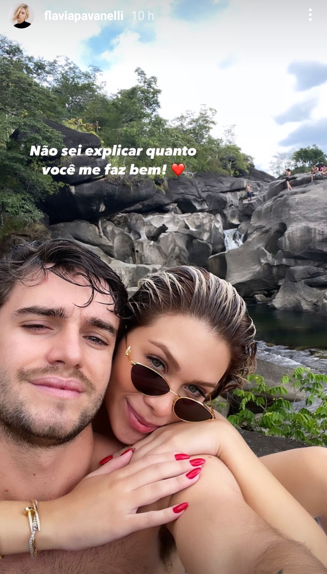 flavia-pavanelli-pepe-cruz-novo-casal Flavia Pavanelli abraçando seu novo affair, Pepe Cruz. Ela está por trás dele e usa um óculos de sol. A expressão facial dele é séria. Ao fundo deles, há um cenário de natureza.