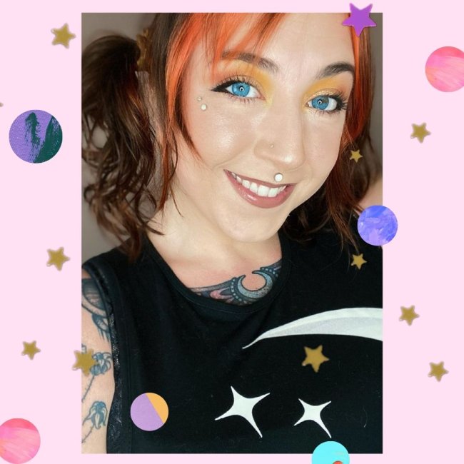 Delineado cachorrinho Jovem com expressão sorridente posando para selfie, usando regata preta, com cabelo colorido, e usando sombra amarela com delineado preto.