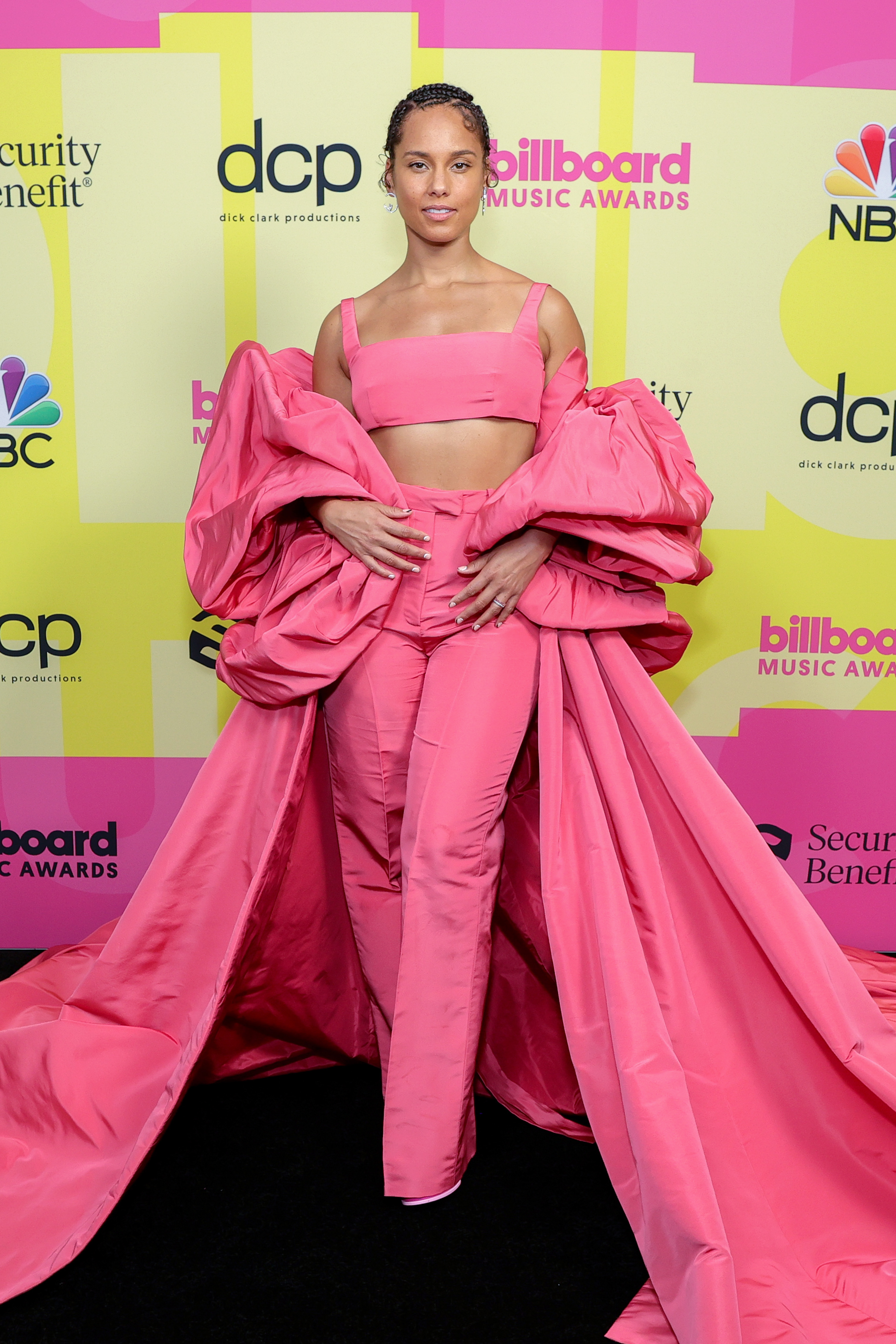 Alicia Keys no Billboard Music Awards 2021. Ela está usando um look todo rosa com top cropped, calça de alfaiataria e uma espécie de capa volumosa por cima.