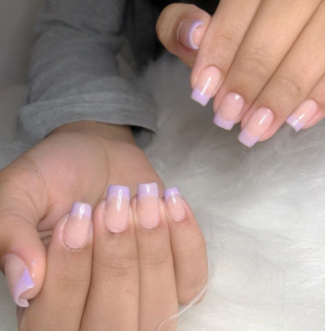 Foto mostrando uma mão com os dedos dobrados para evidenciar as unhas pintadas em francesinha colorida na cor lilás.