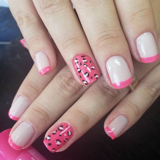 Foto mostrando uma mão com os dedos dobrados para evidenciar as unhas pintadas em francesinha colorida rosa, sendo uma das unhas filha única com animal print