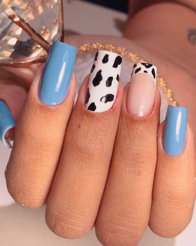 Foto mostrando uma mão com os dedos dobrados para evidenciar as unhas pintadas em francesinha colorida nas cores azul, e uma unha filha única com estampa animal print e outra com francesinha usando animal print.