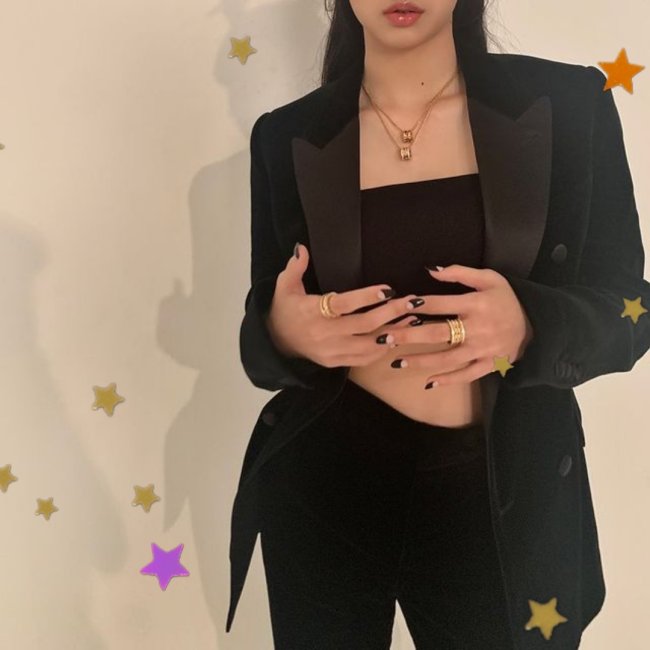 LOOK BLACKPINK LISA Lisa, integrante do grupo Blackpink, porém nesta foto não conseguimos ver seu rosto apenas da sua boca para baixo, ela posa segurando as mãos, usando blazer preto, calça preta e top.