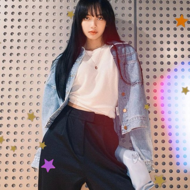 Lisa do BLACKPINK Lisa, integrante do grupo Blackpink, encostada na parede com aparência séria, com o cabelo escurto, usando jaqueta jeans clara, blusa branca e calça azul.