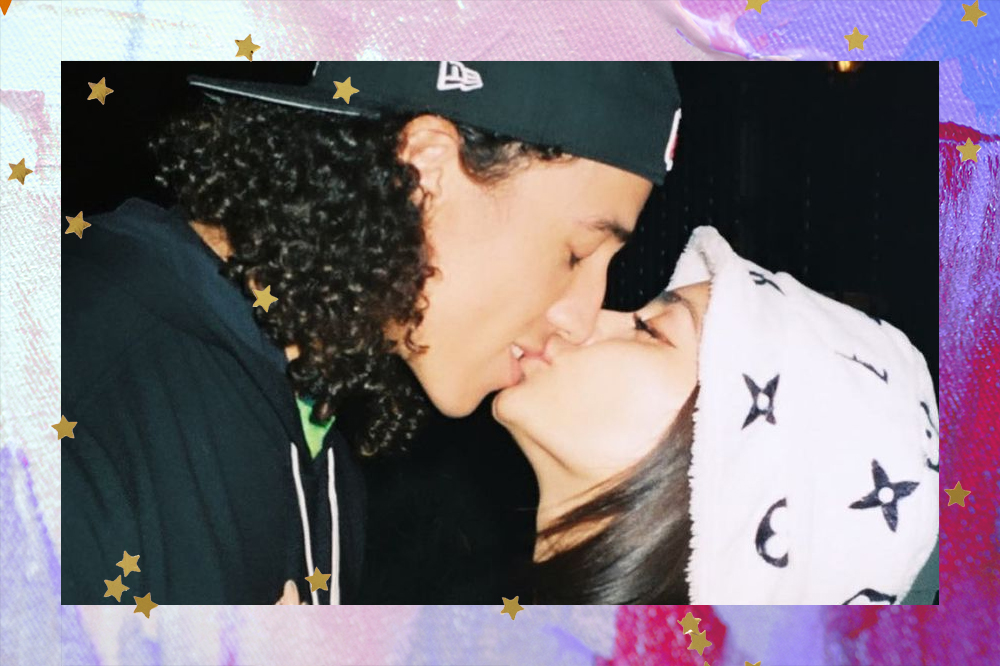 Cole Tucker e Vanessa Hugens se beijando; o jogador está usando moletom e boné preto e a atriz está de chapéu branco com estrelas pretas de detalhe; a moldura da imagem é uma textura de tintas em tons de roxo, rosa e azul com estrelas amarelas de decoração