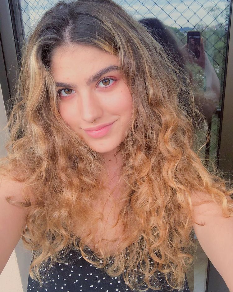 gigrigio_cabelo_loiro Selfie da atriz Giovanna Grigio. Ela usa uma blusa preta com bolinhas brancas, cabelo solto e loiro. Ela olha para a câmera e sorri.