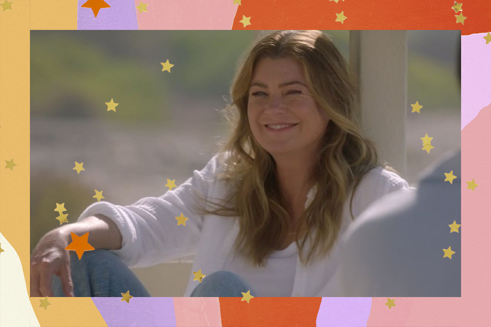 Ellen Pompeo, como Meredith Grey em "Grey's Anatomy", sentada com os joelhos dobrados, a mão sob o joelho direito. Ela está sorrindo.