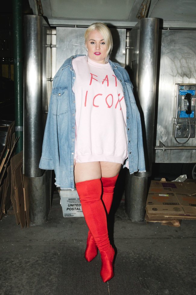 look over the knee Jove posando com blusa jeans aberta, camiseta por dentro, e bota over the knee vermelha.