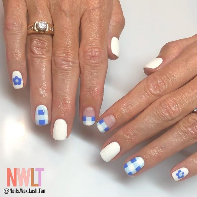 Foto de duas mãos com anel no dedo anelar da mão direita. Ambas as mãos estão com uma nail art xadrez azul e branco.