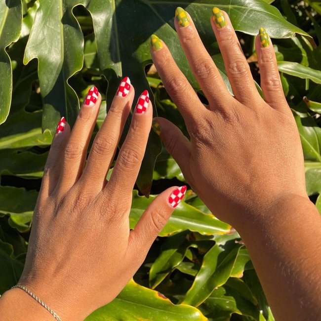unha xadrez colorida Foto de duas mãos. A mão esquerda está com a unha pintada em uma nail art xadrez branco e vermelho. A mão direita está com a unha pintada em uma nail art xadrez amarelo e verde.