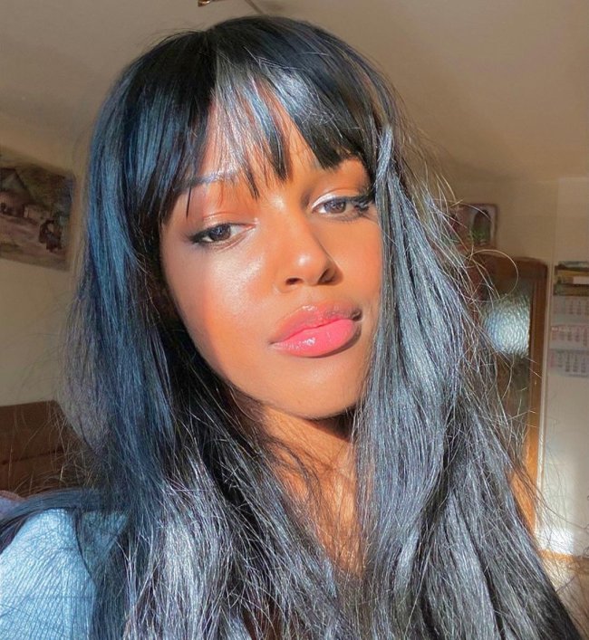cabelo com franja reta Selfie de uma mulher. Ela está com o cabelo com uma franja reta solto e com gloss. Ela olha para a câmera e não sorri.