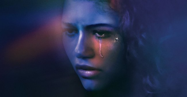 euphoria Foto do rosto da personagem Rue da série da HBO, Euphoria. Ela olha para frente, está com uma lágrima escorrendo no olho esquerdo e a fotografia tem tons de azul e roxo.