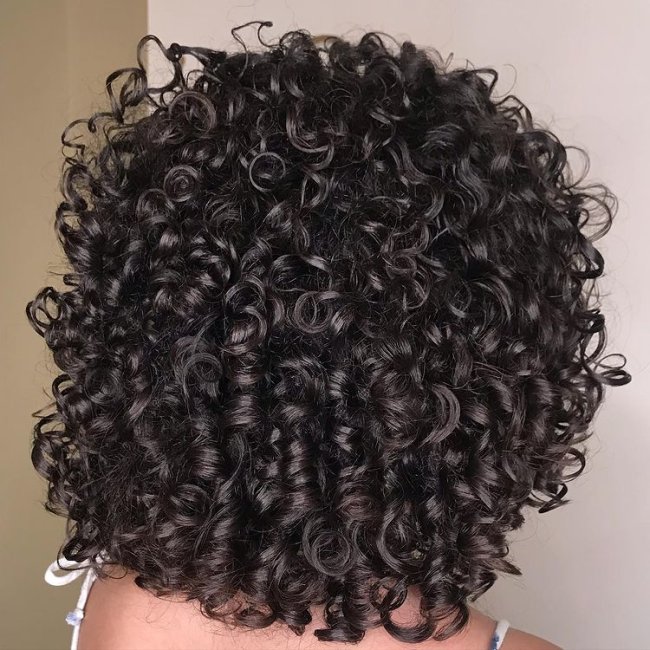 long bob reto cacheado Mulher está de costas e não conseguimos ver seu rosto, somente seu cabelo com corte bob na cor castanha