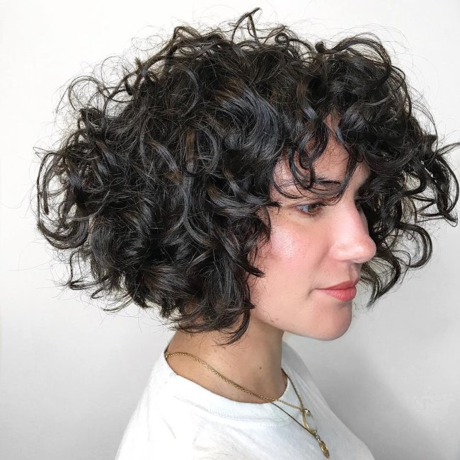 long bob Jovem com expressão levemente sorridente, exibindo seu corte bob, usando blusa branca e olhando para o lado direito.