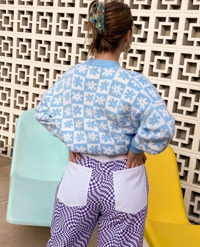 look mix de estampas avant basic Foto de uma mulher de costas. Ela usa um cardigan branco com estampa azul, calça com estampa psicodélica em um azul mais escuro.