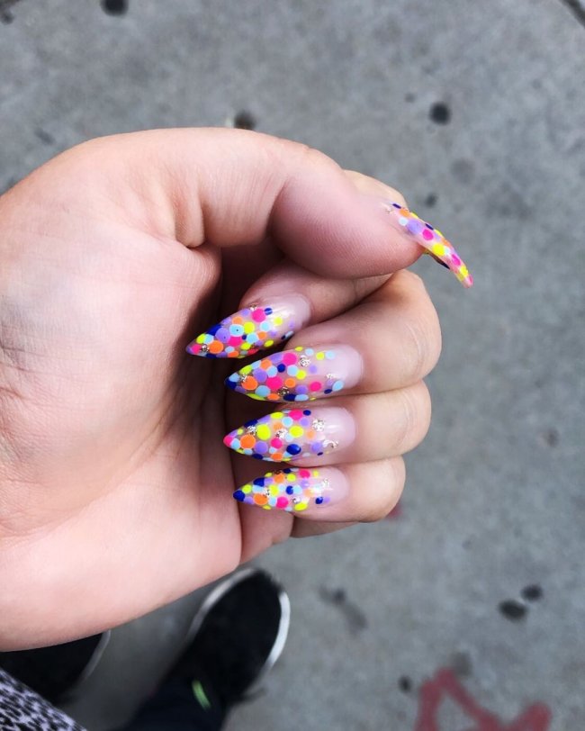Foto com destaque nas unhas com nail art de bolinha, dessa vez com bolinhas na ponta da unha nas cores amarelo, azul, rosa, verde e laranja.
