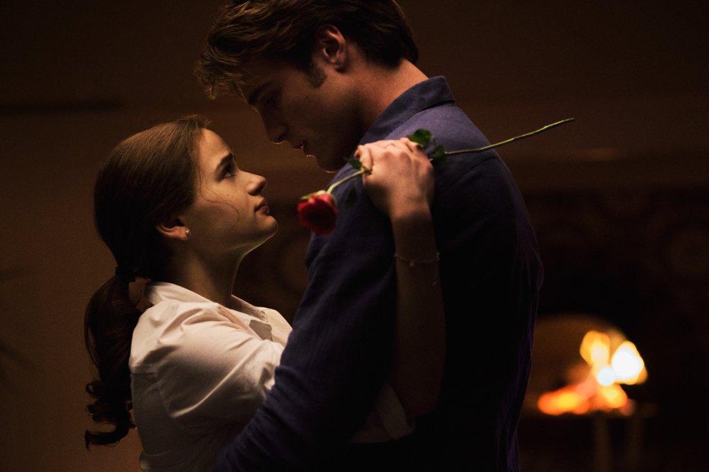 Joey King como Elle e Jacob Elordi como Noah em cena de A Barraca do Beijo 3; os dois estão abraçados se encarando em um ambiente à meia luz; Elle está com uma roupa branca segurando uma rosa e Noah está de camisa azul escura