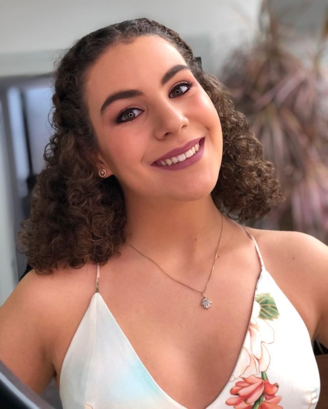 penteado meio preso curto Jovem sorridente usando blusa de alça, e colar.