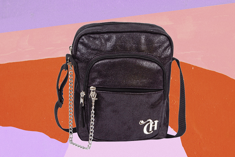 taurina-bolsa-cross-rock-sestini Bolsa cross rock preta pequena com detalhe de correntes da CAPRICHO com a Sestini em fundo laranja, lilás e rosa
