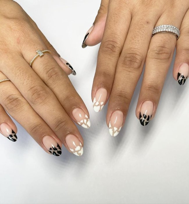 Foto com close nas unhas e tem nail art com espaço negativo nas cores preta e branca.