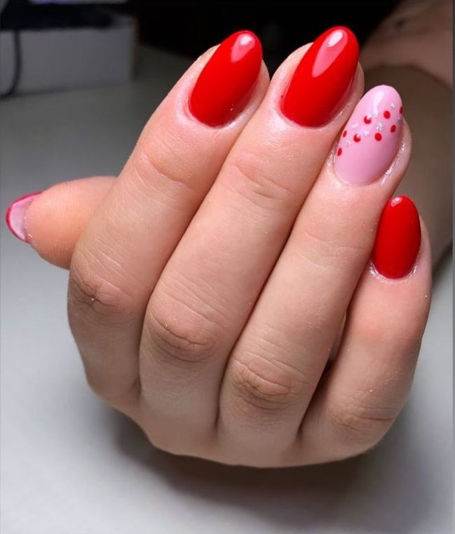 Foto com destaque na mão mostrando as unhas com esmalte vermelho.