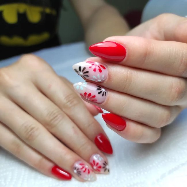unha vermelha com desenho de flor Foto com foco nas mãos exibindo a nail art das unhas. No caso, unha vermelha com detalhe de flores.