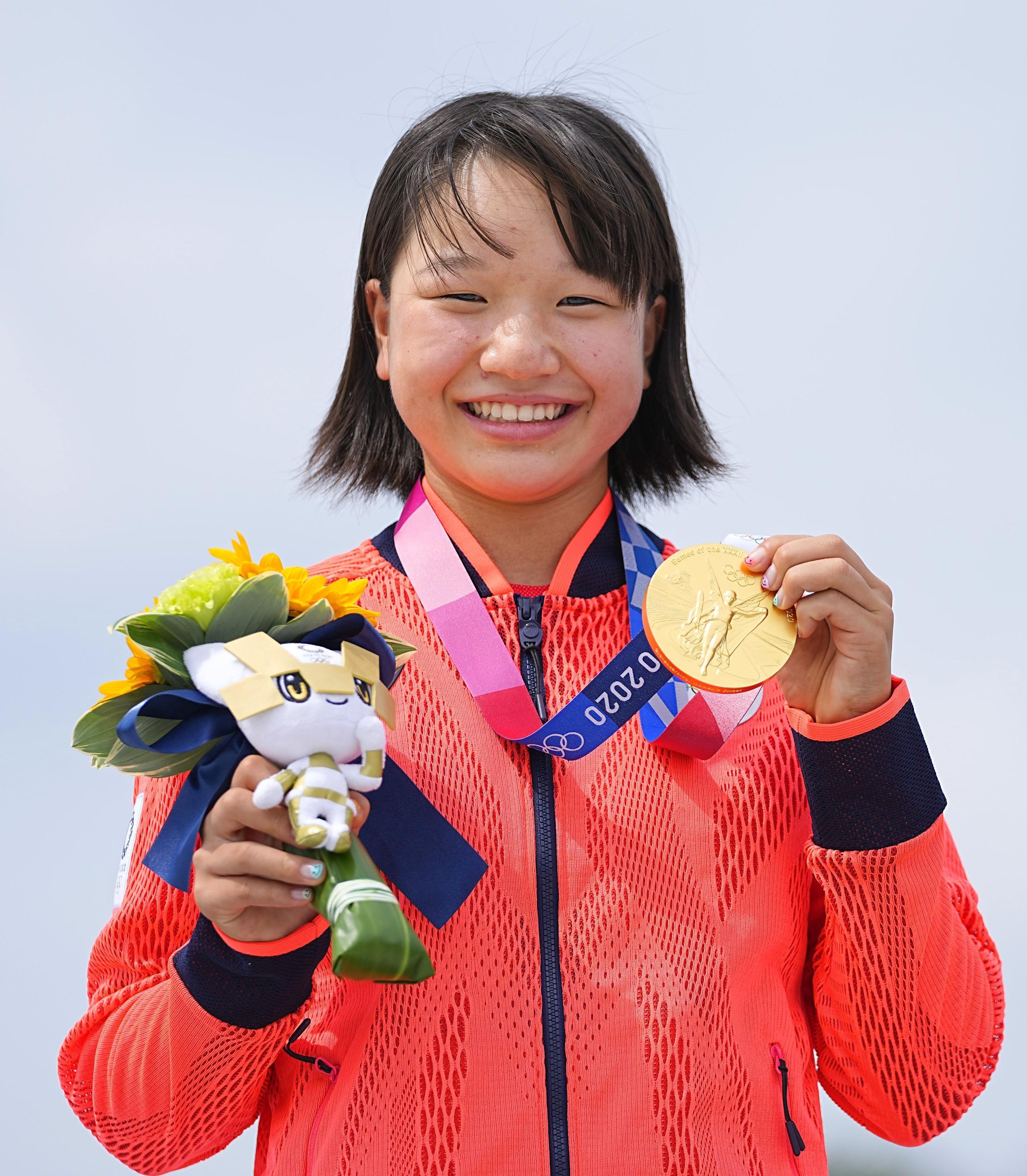 A skatista japonesa Momiji Nishiya, de 13 anos, sorrindo enquanto segura sua medalha de ouro e o mascote das Olimpíadas de Tóquio 2020.