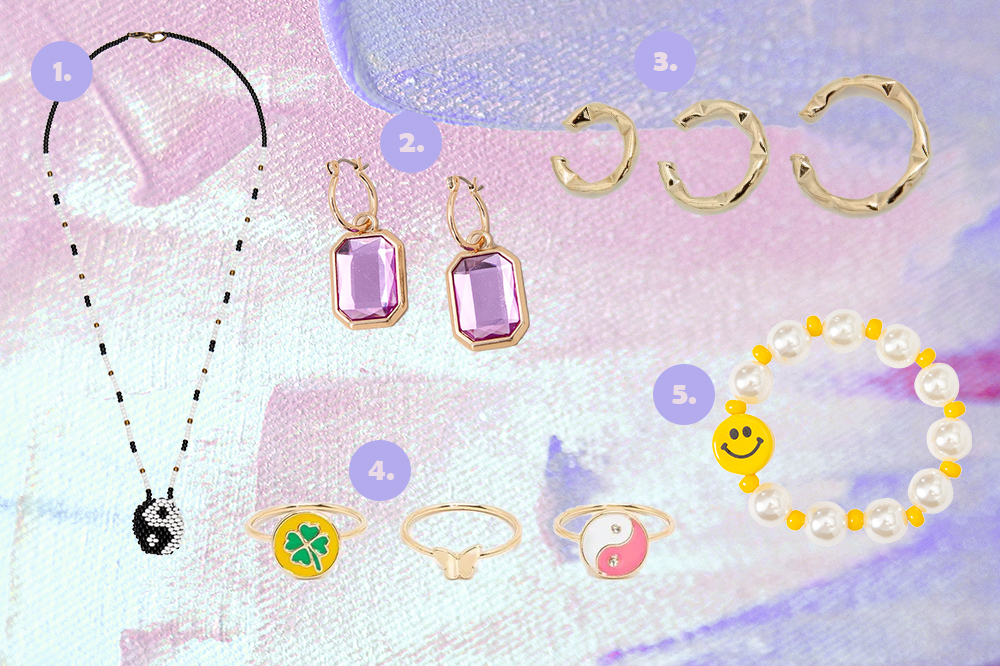 acessorios-colares-pulseiras-brincos-aneis-01 Montagem em fundo lilás e rosa com cinco opções de acessórios. Colar com símbolo yin yang feito à mão, brinco lilás, ear hooks dourados, kit de três anéis e pulseira de pérolas com carinha feliz.