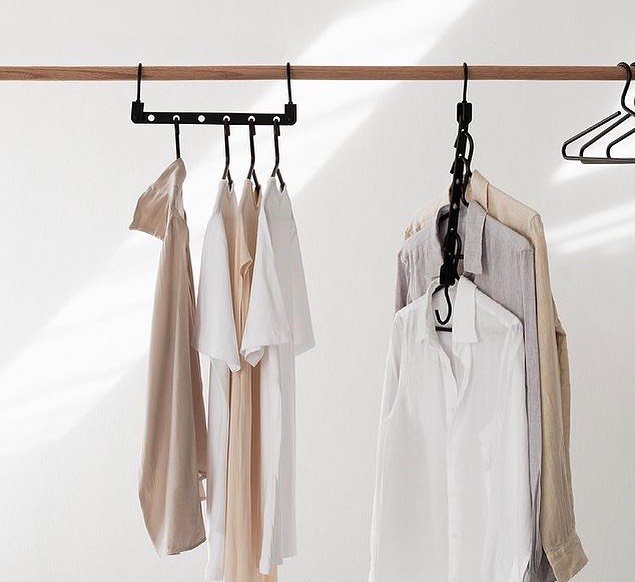 guarda-roupa Foto com parede branca e algumas peças penduradas em uma arara de madeira.