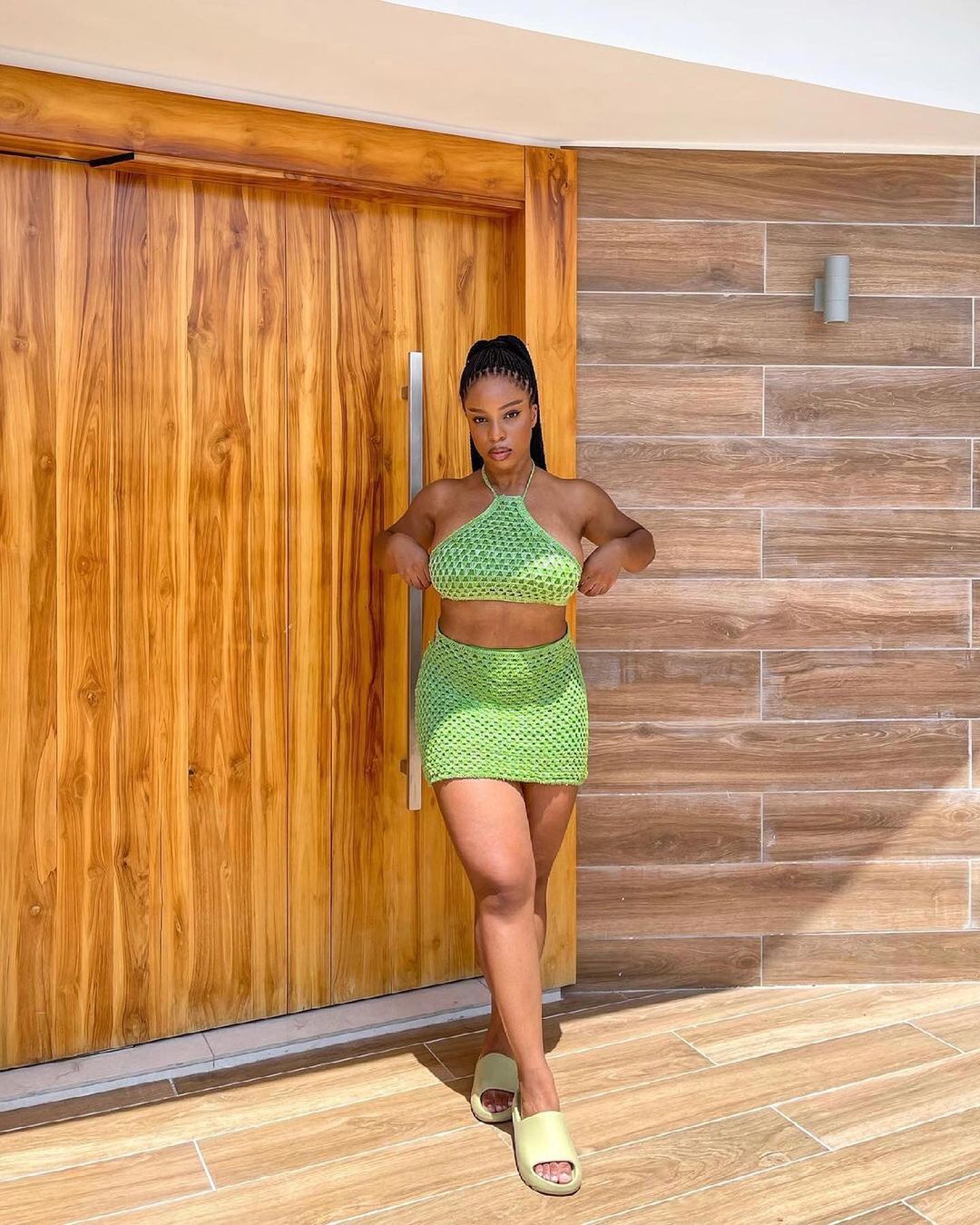 look monocromatico com chinelo nuvem Jovem com expressão séria e mãos para trás do corpo posando para foto com conjunto verde.