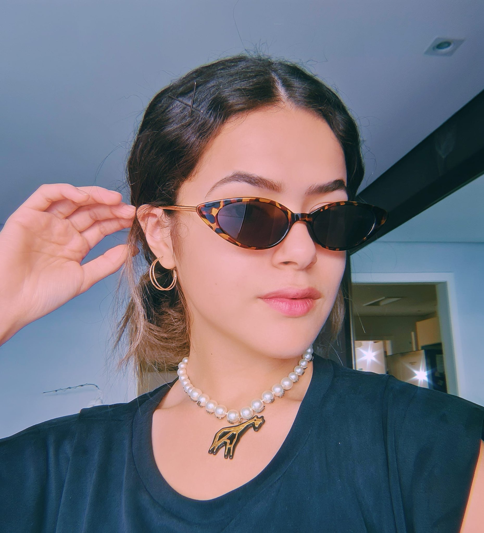 maisa-silva-acessorios-oculos-de-sol- Maisa Silva usando óculos de sol e colar de pérolas com camiseta cinza