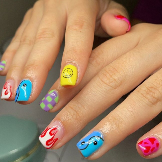 unha colorida com desenhos simples Foto com close nas unhas com esmaltes coloridos em diversas cores.