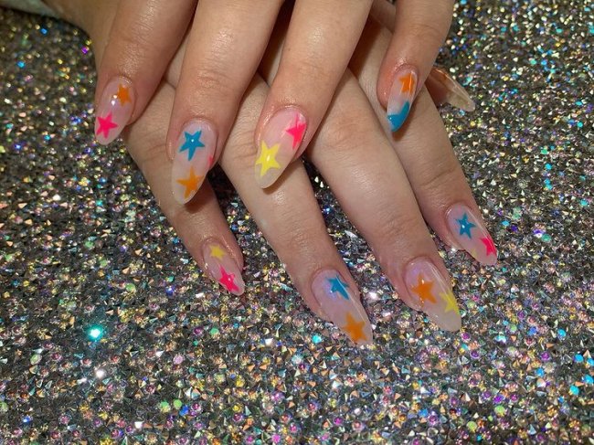 unha com estrela colorida Foto com close nas unhas com esmaltes coloridos em diversas cores.