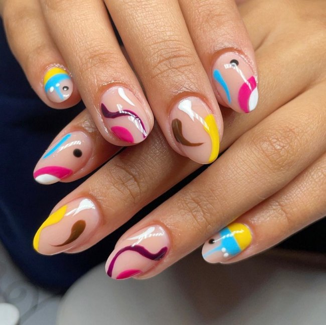 Foto com close nas unhas com esmaltes coloridos em diversas cores.