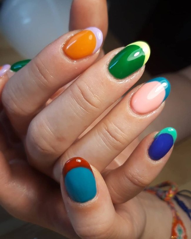 Foto com close nas unhas com esmaltes coloridos em diversas cores.