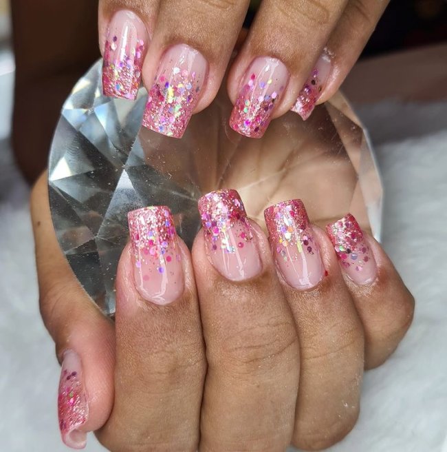 Francesinha com glitter cor de rosa Foto com foco nas unhas mostrando a francesinha com glitter.
