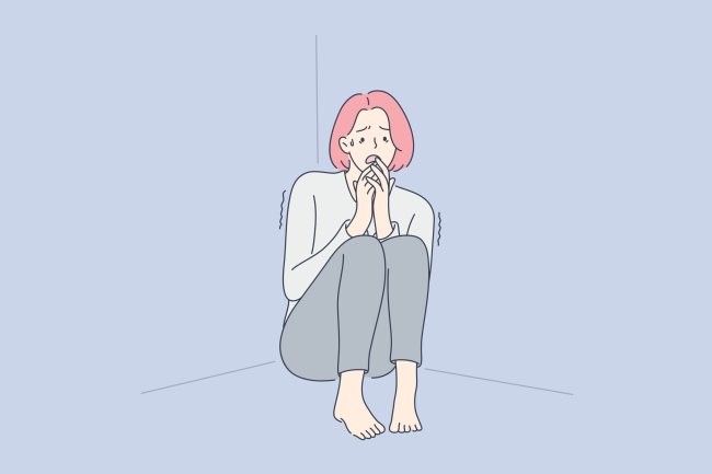 Síndrome da Caverna: o que é, sintomas, tratamento e relação com pandemias Ilustração de uma mulher ruiva, encolhida no cantor da casa, com medo de sair