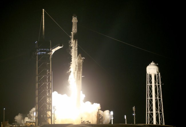 Foguete Falcon, da missão Inspiration4, decolando na Flórida, nos EUA. Está de noite e há muito fogo saindo da parte traseira da espaçonave