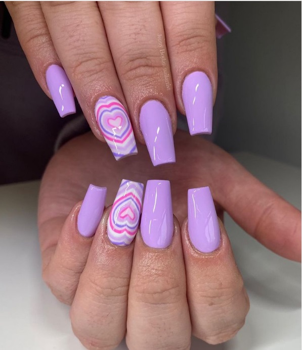 Foto com foco nas unhas exibindo a nail art chamada bubble heart, que traz vários corações um dentro do outro.