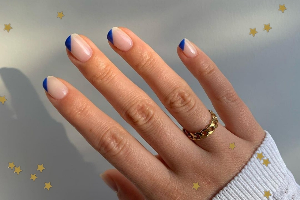 Foto com foco nas mãos com unhas com espaço negativo e um detalhe em azul.