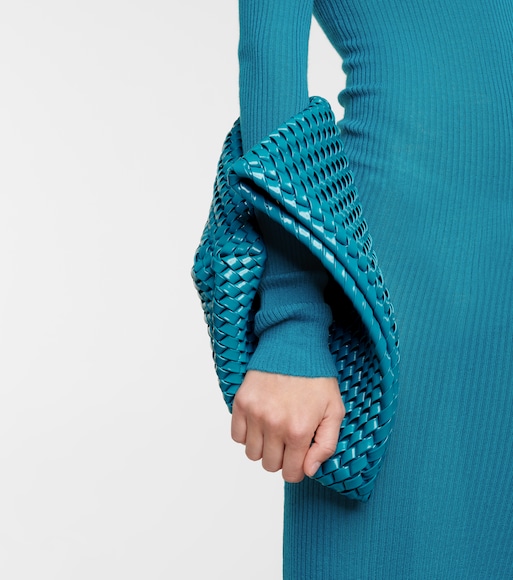 bolsa-bottega-veneta Braço de modelo usando vestido azul de manga longa e segurando bolsa da mesma cor ao redor do braço