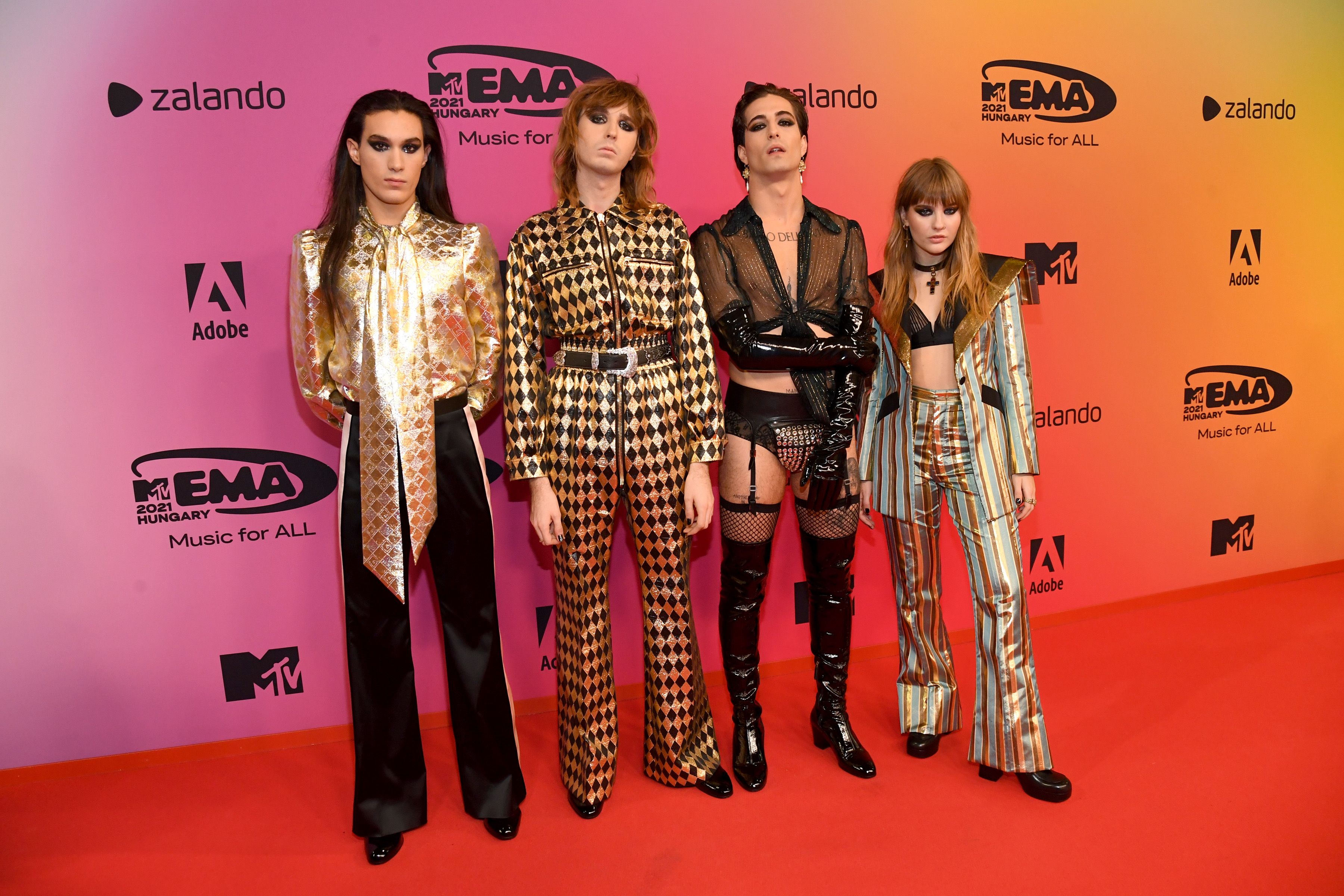 Maneskin posando na frente dos logos da MTV EMA com peças diferentes e com transparência.