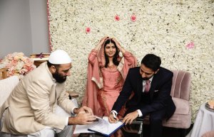 Malala se casa em uma íntima e tradicional cerimônia muçulmana; veja fotos Foto do casamento de Malala. A família está reunida em frente a uma parede de rosas brancas. Todos sorriem.