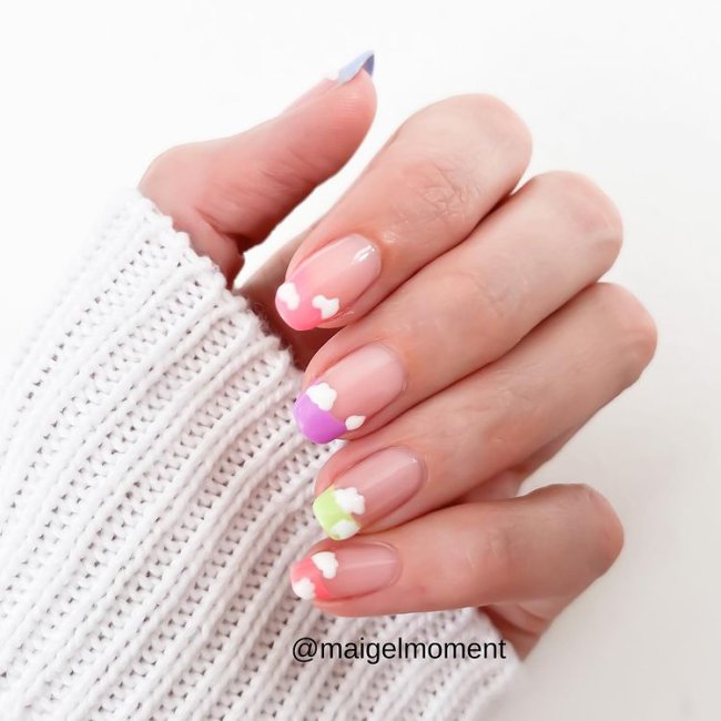 francesinhas coloridas com decoracao de nuvens Foto de uma mão com as unhas decoradas com francesinha colorida e desenhos de nuvens brancas.